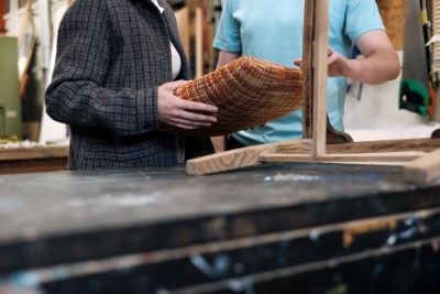 Two people upholstering a chair