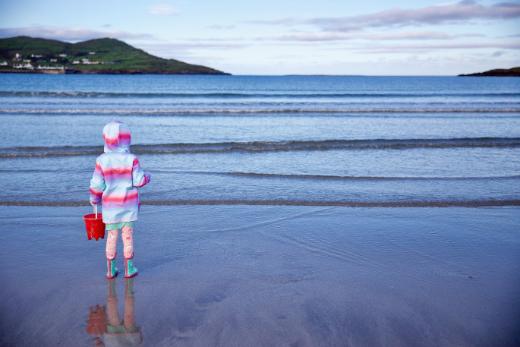 A girl in a colorful raincoat by the sea
